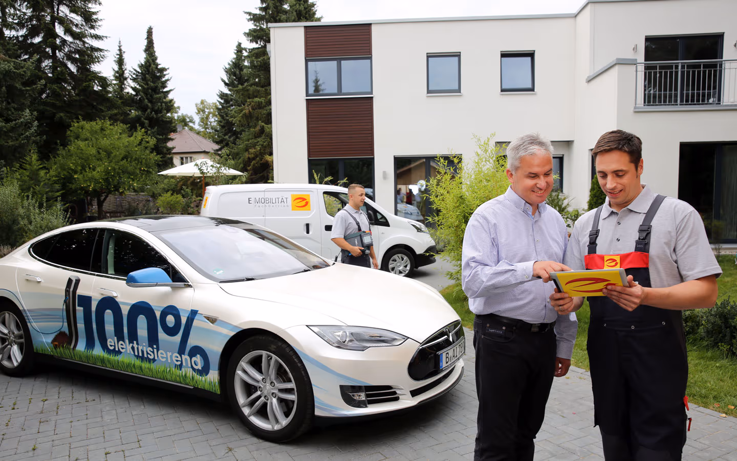 E-Mobilität - Mitarbeiter mit Kunden vor Elektrofahrzeugen 100% elektrisch &middot; Hornetz